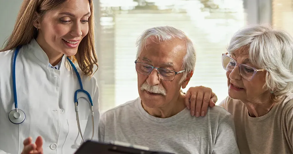 A senior couple with a doctor looking at a screen together in a medical setting. 
