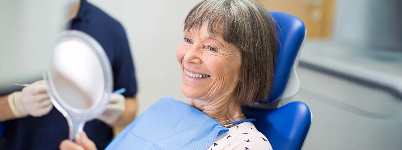 woman smiling in mirror at dentist