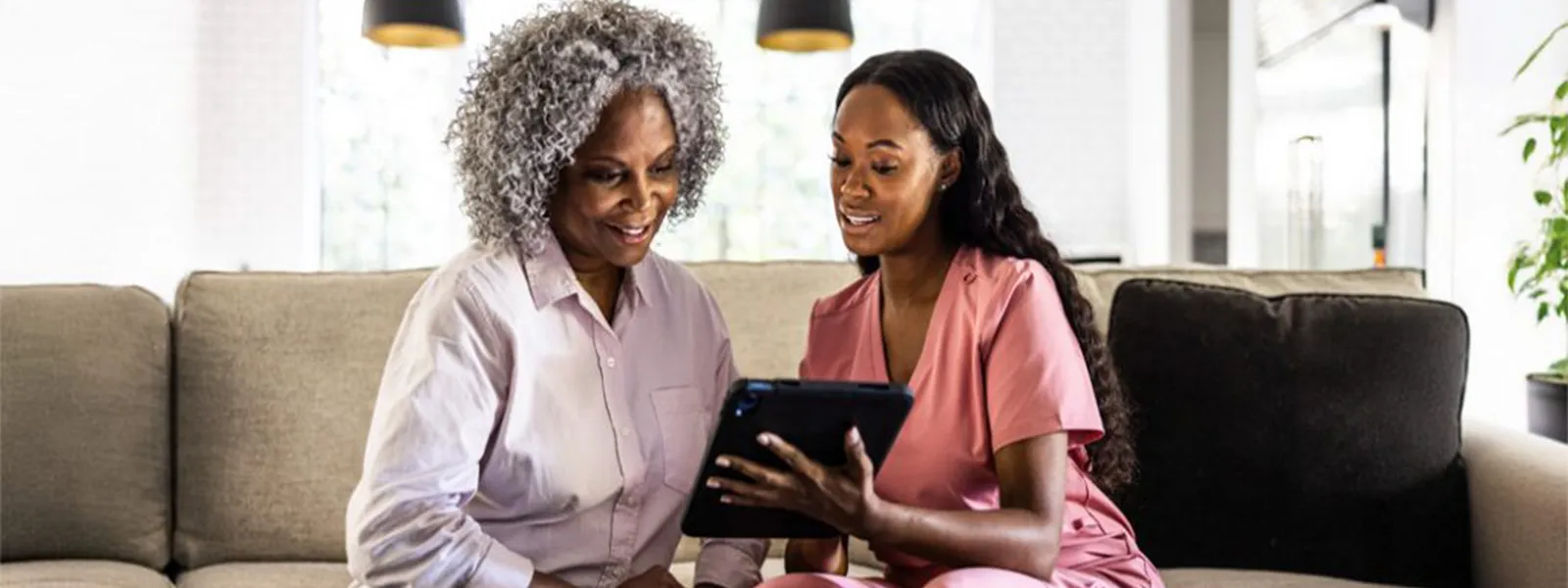 Nurse helping senior woman with documents on a tablet.