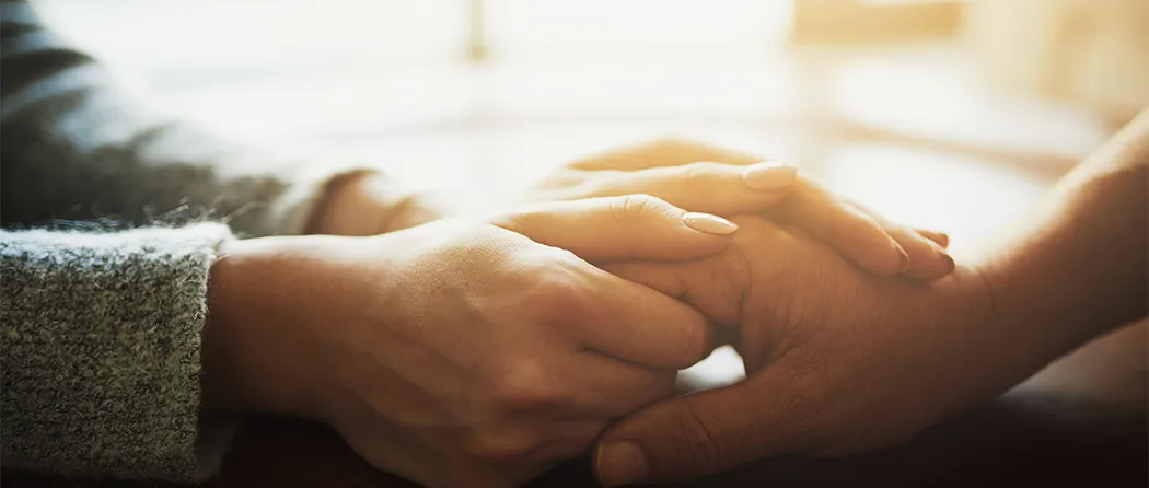 Close-up of hands held together, showing support and care