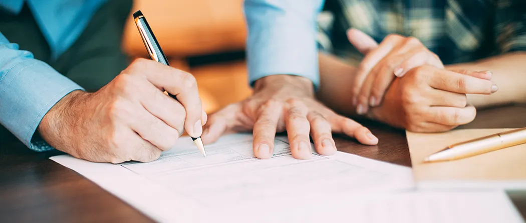 Zoomed in photo of someone signing paperwork