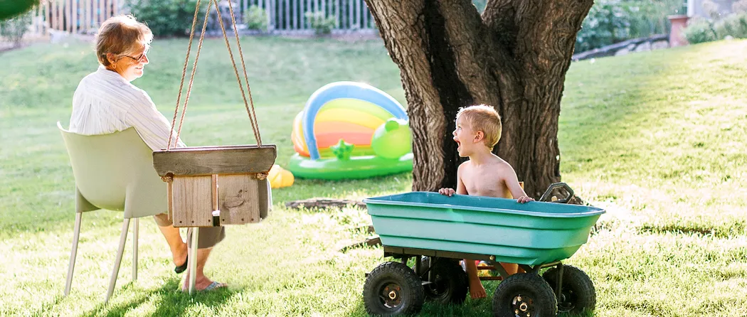 Grandma and grandson playing in the backyard with wheelbarrow