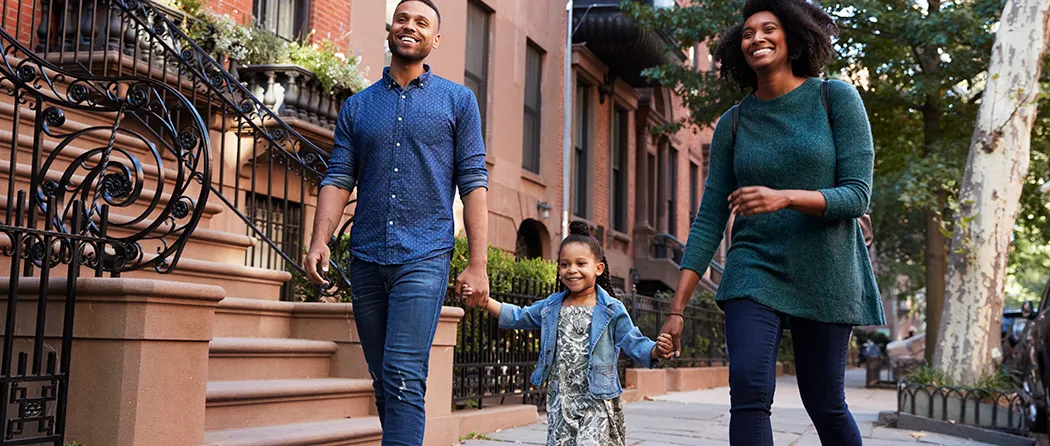 Mom and dad holding hands with daughter walking down the sidewalk