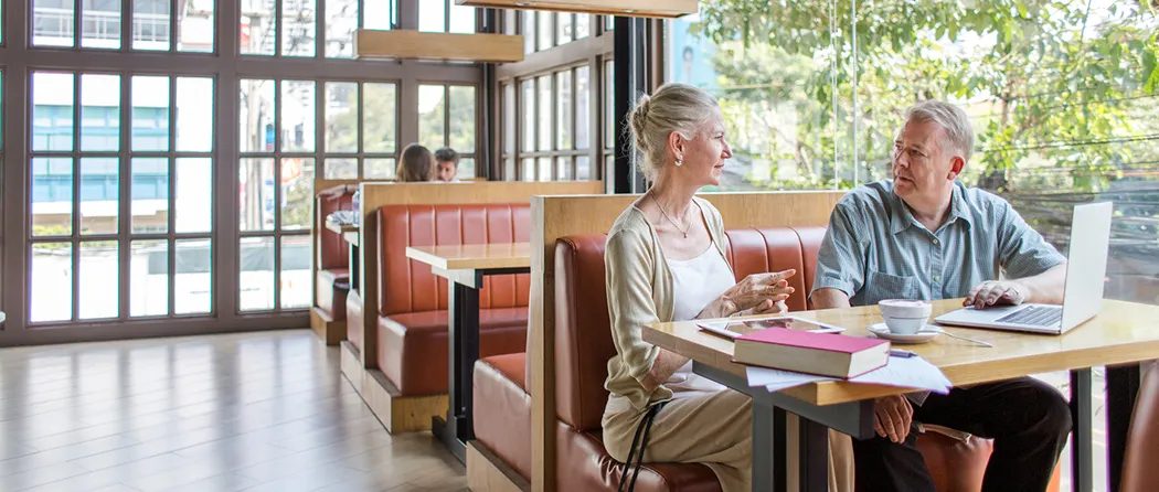 A couple sitting in a restaurant booth looking at each other. 