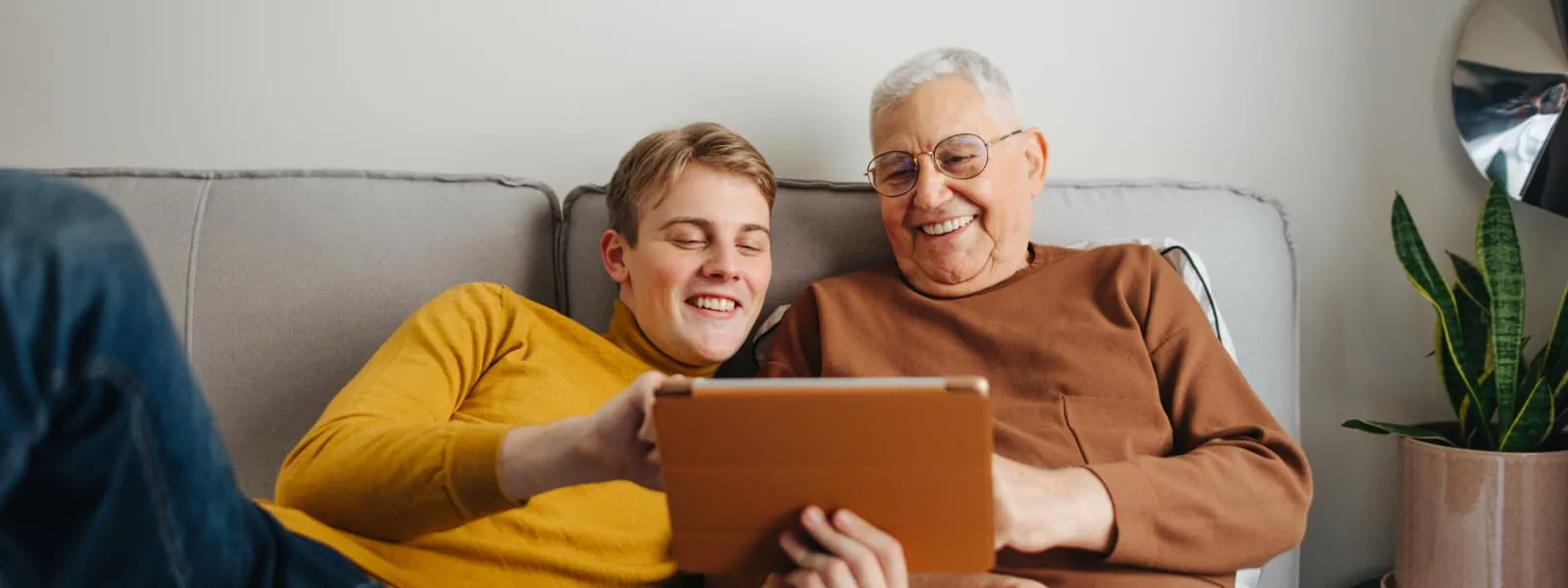 Image of a grandfather and grandson laughing looking at an iPad.