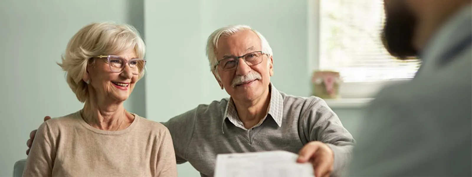 smiling senior couple handing over documents
