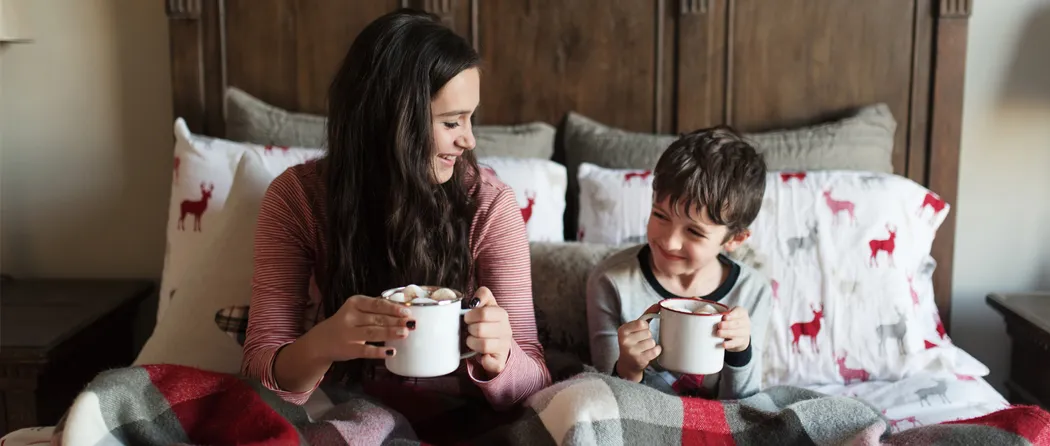 Mom and son in bed drinking hot chocolates