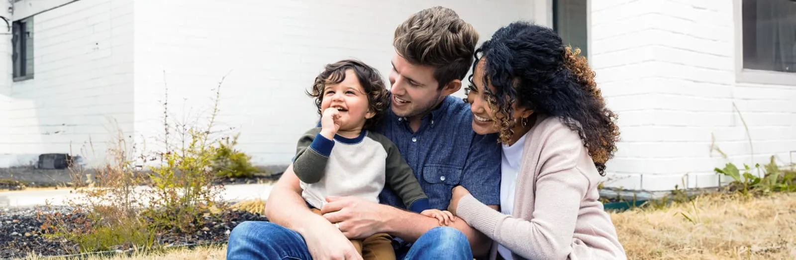 Family laughing in front of house