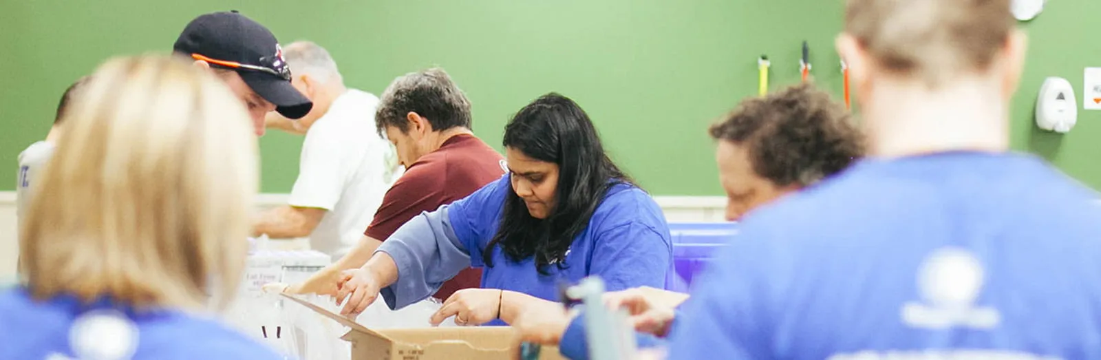 Group of people in blue shirts with sealing boxes