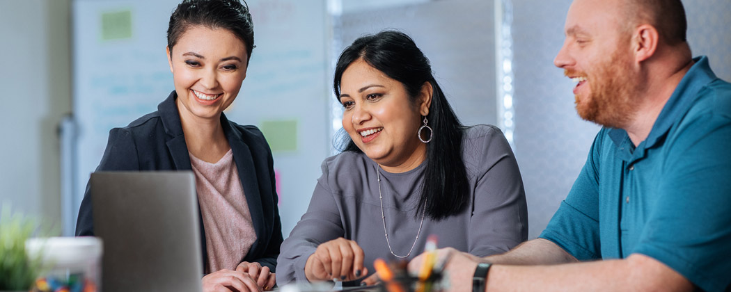 three coworkers looking at a laptop