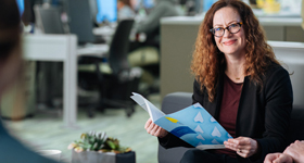 woman looking at coworker holding a folder