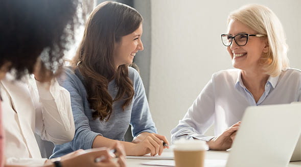 three women laughing together at desk