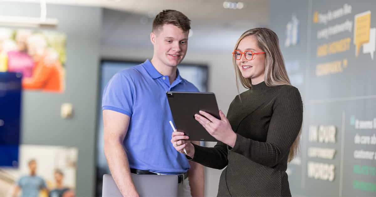 two coworkers looking at a tablet device