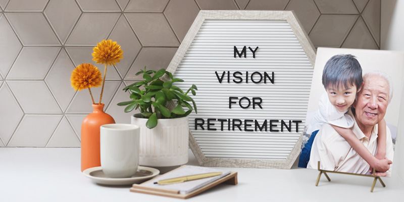 A small decorative sign that says "My vision for retirement" sits on a table next to two plants, a tea cup, and a notebook and pen.