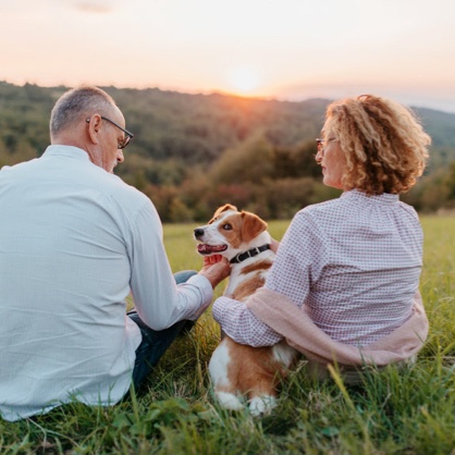 A couple sitting with their dog watching the sunset.