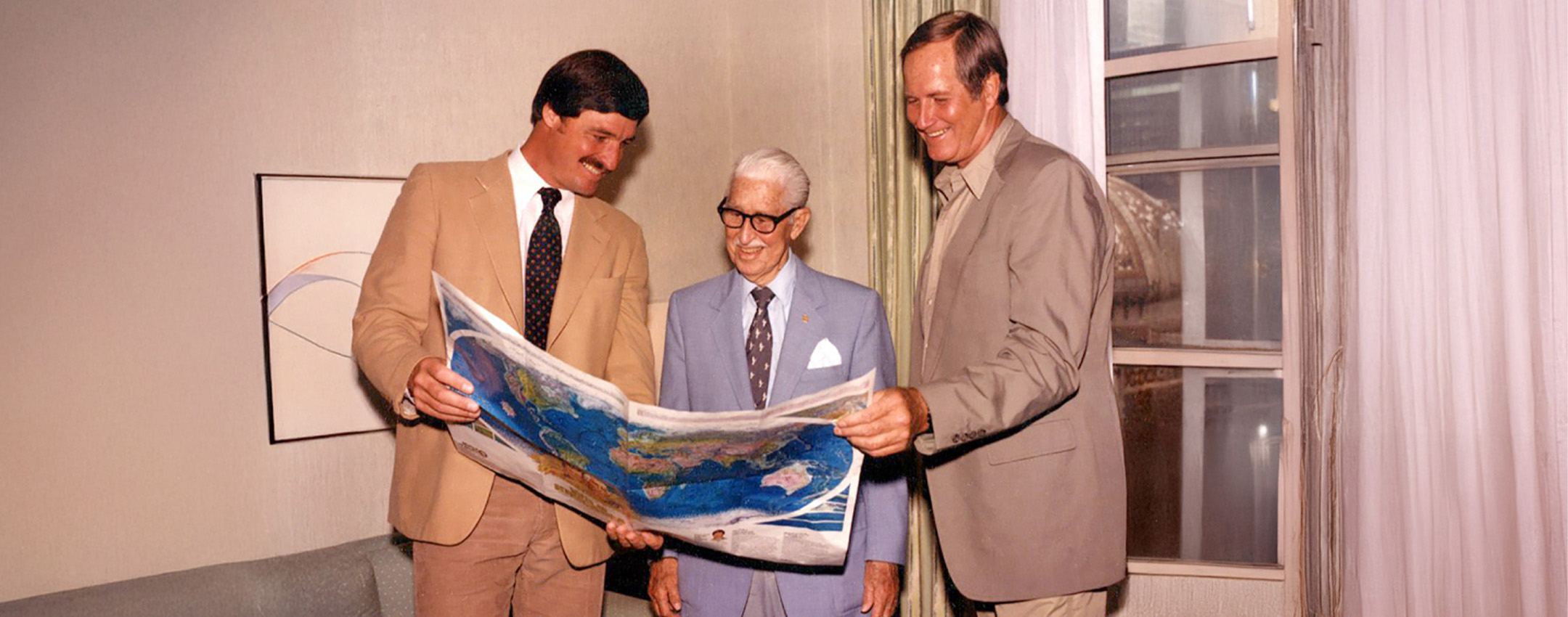 Wild Kingdom hosts across the decades together looking at a world map: Peter Gros, Marlin Perkins, and Jim Fowler.