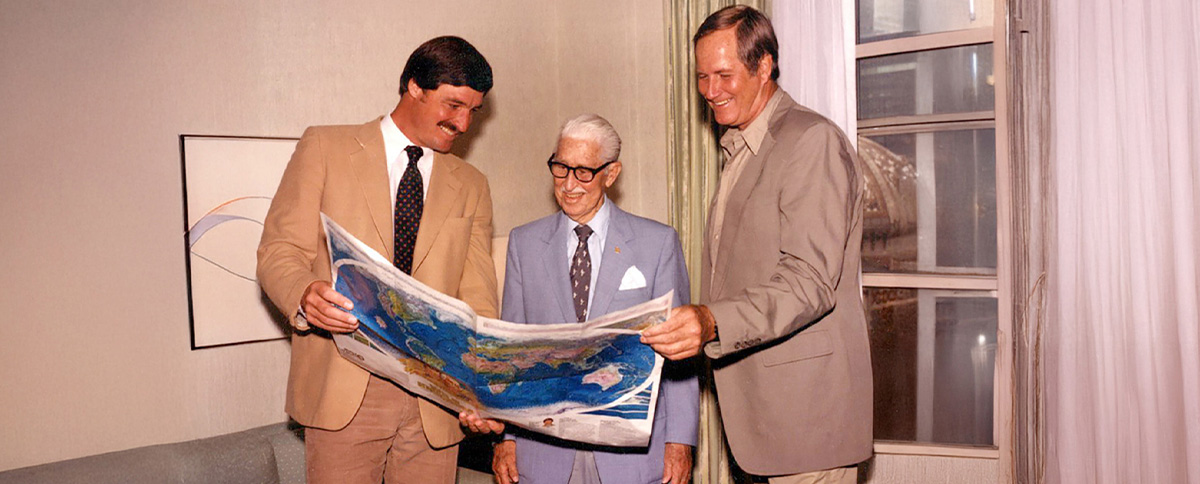 Wild Kingdom hosts across the decades together looking at a world map: Peter Gros, Marlin Perkins, and Jim Fowler.