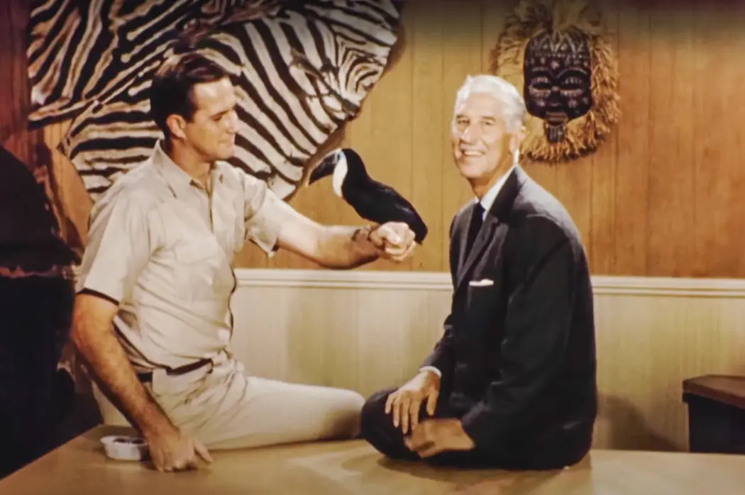 Jim Fowler and Marlin Perkins holding a tropical bird on the original set of Mutual of Omaha's Wild Kingdom.